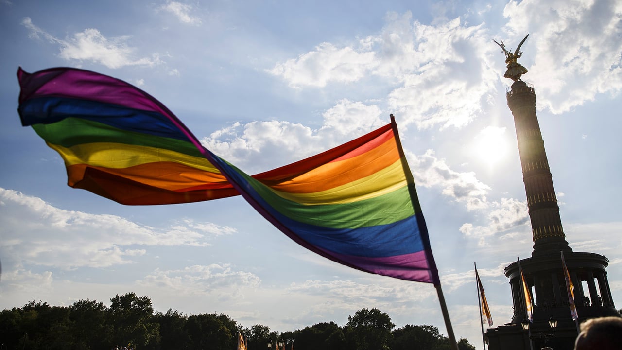 Ein Teilnehmer schwenkt die Regenbogen-Flagge auf dem 40. Christopher Street Day vor der Siegessäule am 28. Juli 2018 in Berlin, Deutschland (© Carsten Koall/Getty Images News) desktop wallpaper