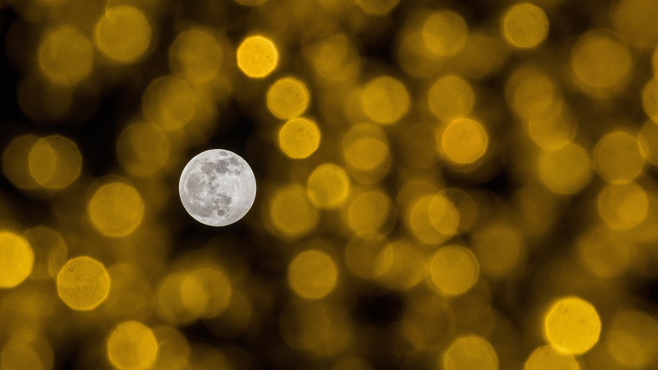 The December full moon seen through holiday lights (© Jesus Merida/Getty Images) desktop wallpaper