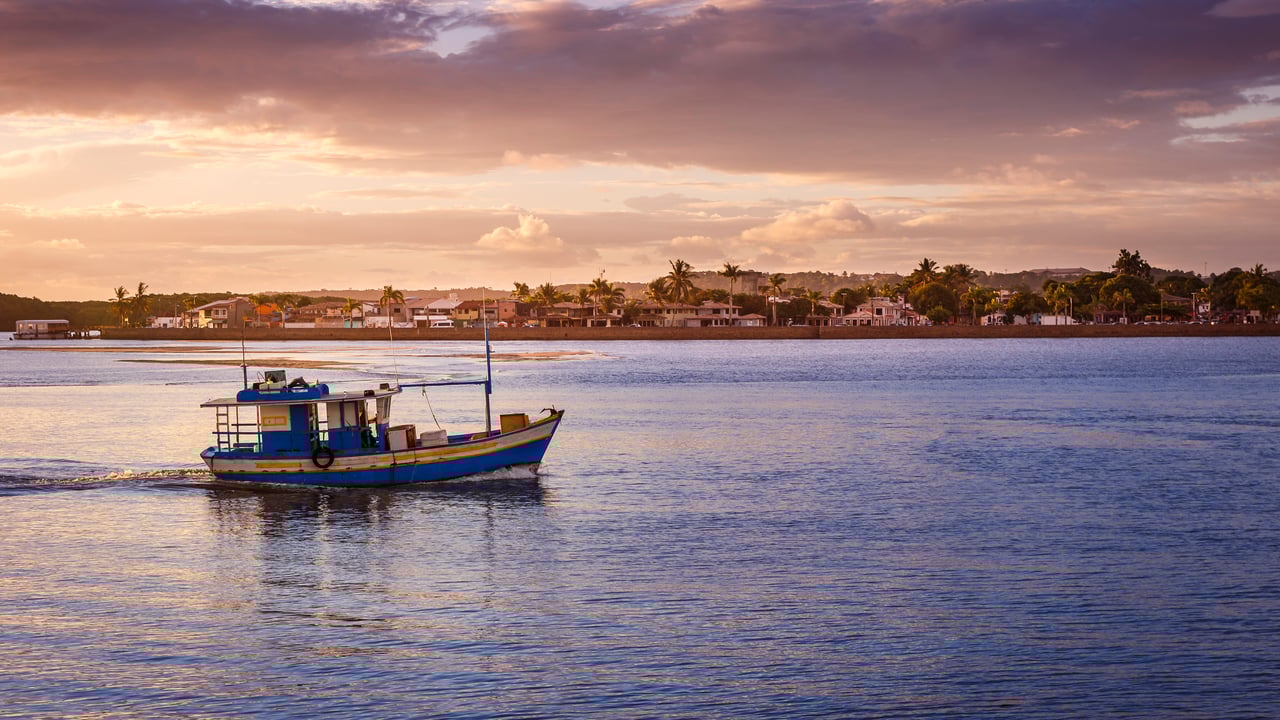 Barco de pescadores flutuando em um rio durante o pôr do sol (© agustavop/iStock/Getty Images Plus) desktop wallpaper