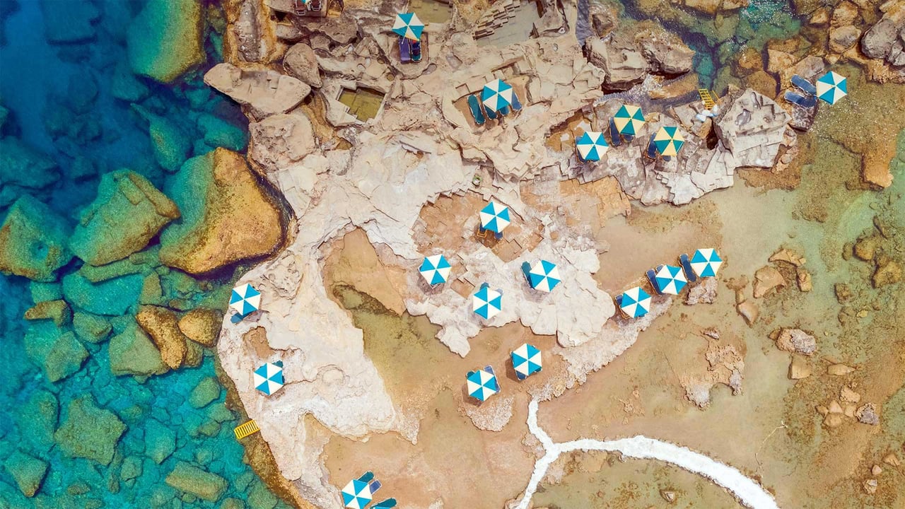 Aerial view of blue and white parasols on the rocky coast of Rhodes, an island in Greece (© Amazing Aerial Agency/Offset by Shutterstock) desktop wallpaper