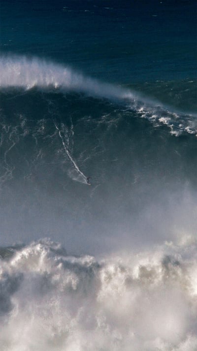 Rodrigo Koxa riding the biggest wave ever surfed, on Nov 8, 2017, off the coast of Nazaré, Portugal (© Pedro Cruz/AP Photo) mobile wallpaper