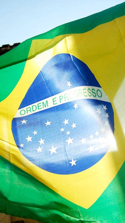 Bandeira brasileira voando sob o céu azul (© GideoniJunior/Getty Images) mobile wallpaper