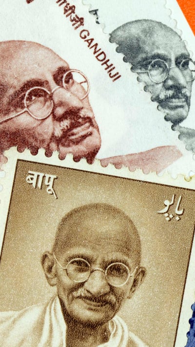 An assortment of postage stamps with images of Mahatma Gandhi (© PictureLake/E+/Getty Images) mobile wallpaper