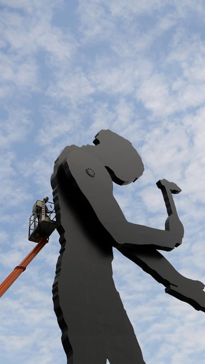 A worker painting the Hammering Man, a sculpture by Jonathan Borofsky, in Frankfurt, Germany (© Arne Dedert/Alamy) mobile wallpaper