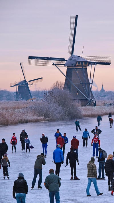 Skating on a frozen canal near the windmills at Kinderdijk, Netherlands (© Lourens Smak/Alamy) mobile wallpaper