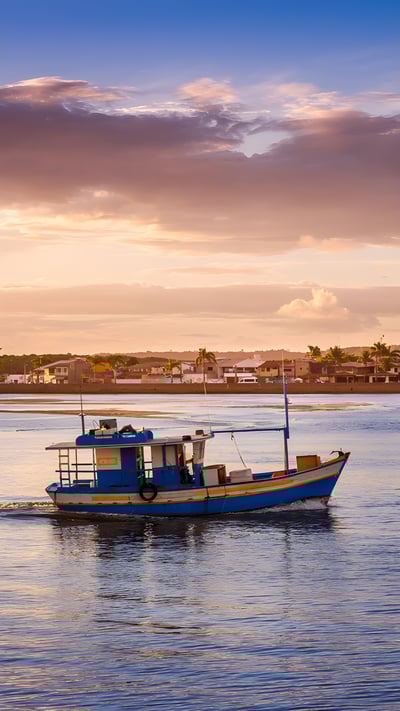 Barco de pescadores flutuando em um rio durante o pôr do sol (© agustavop/iStock/Getty Images Plus) mobile wallpaper