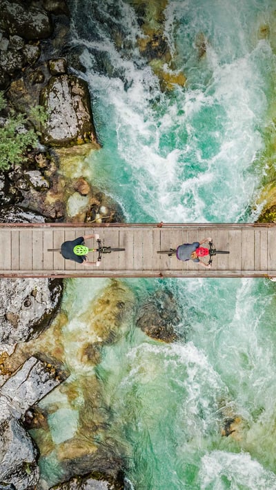 Cyclists on a wooden suspension bridge over the Soča River in Slovenia (© Amazing Aerial Agency/Offset by Shutterstock) mobile wallpaper