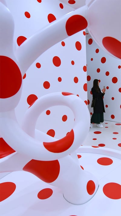 Eine Frau betrachtet Yayoi Kusamas Installation „With All My Love for The Tulips, I Pray Forever, 2011“. Zum Weltkunsttag (© Timothy A. Clary/Getty Images) mobile wallpaper